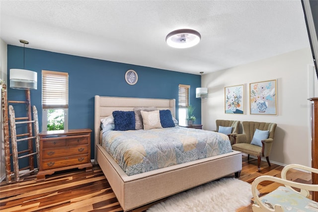 bedroom with hardwood / wood-style floors, a textured ceiling, and multiple windows