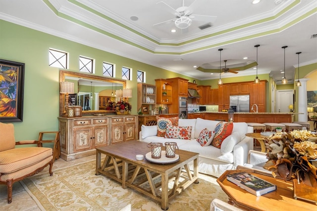 tiled living room featuring ceiling fan, ornamental molding, sink, and a tray ceiling