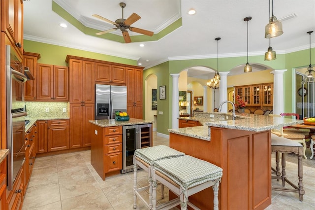 kitchen featuring a tray ceiling, beverage cooler, a large island, hanging light fixtures, and built in fridge