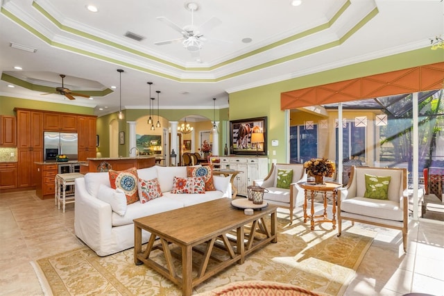 tiled living room with ceiling fan with notable chandelier, a raised ceiling, and ornamental molding