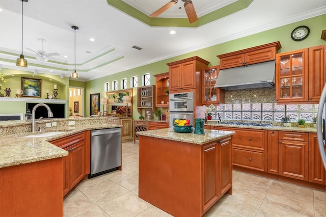 kitchen with a raised ceiling, pendant lighting, stainless steel appliances, and ornamental molding