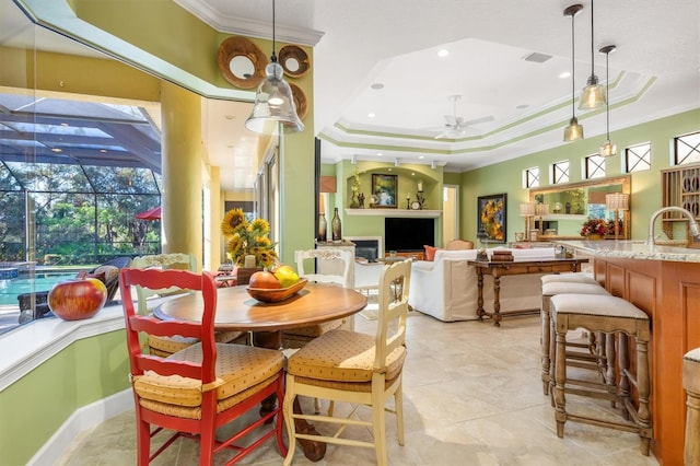 dining room with a raised ceiling, ceiling fan, plenty of natural light, and ornamental molding