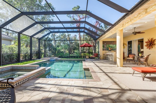 view of pool with glass enclosure, ceiling fan, an in ground hot tub, a bar, and a patio