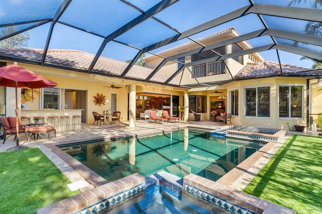 rear view of house with glass enclosure, an outdoor bar, ceiling fan, and a patio area