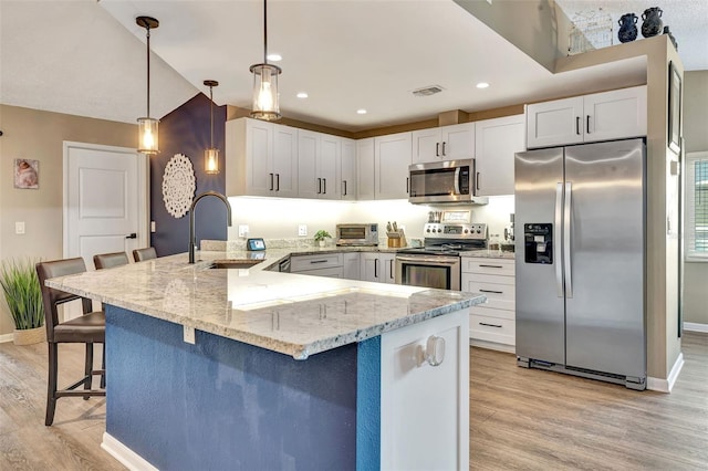 kitchen with stainless steel appliances, hanging light fixtures, kitchen peninsula, a breakfast bar, and sink