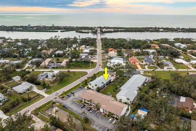 aerial view at dusk featuring a water view