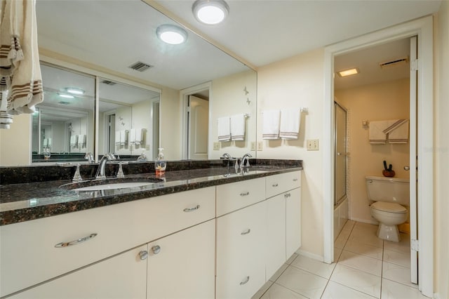 full bathroom with toilet, vanity, tile patterned floors, and bath / shower combo with glass door