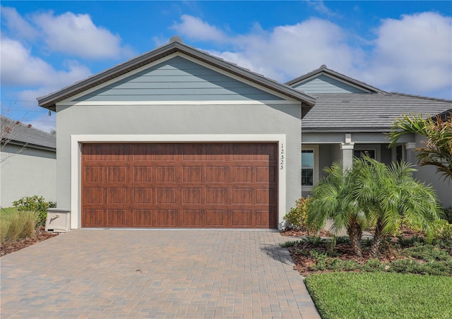 ranch-style house with decorative driveway, an attached garage, and stucco siding