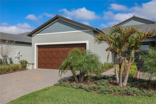 view of front of home featuring decorative driveway, an attached garage, and stucco siding