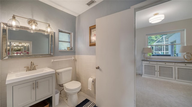 bathroom featuring vanity, tile walls, and toilet