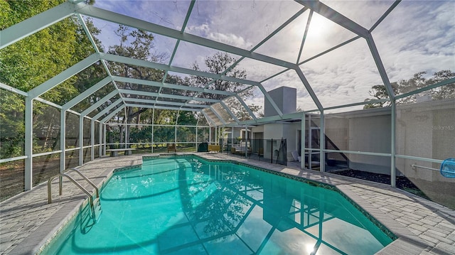 view of swimming pool featuring a patio and glass enclosure