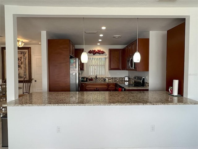 kitchen with pendant lighting, sink, appliances with stainless steel finishes, light stone counters, and kitchen peninsula