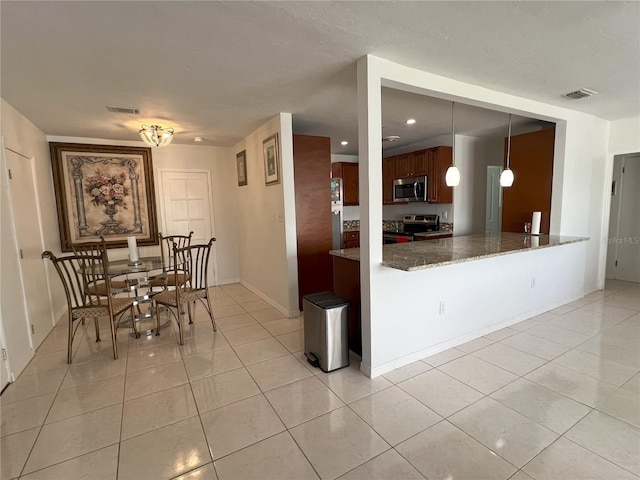 kitchen featuring hanging light fixtures, dark stone countertops, light tile patterned floors, appliances with stainless steel finishes, and kitchen peninsula