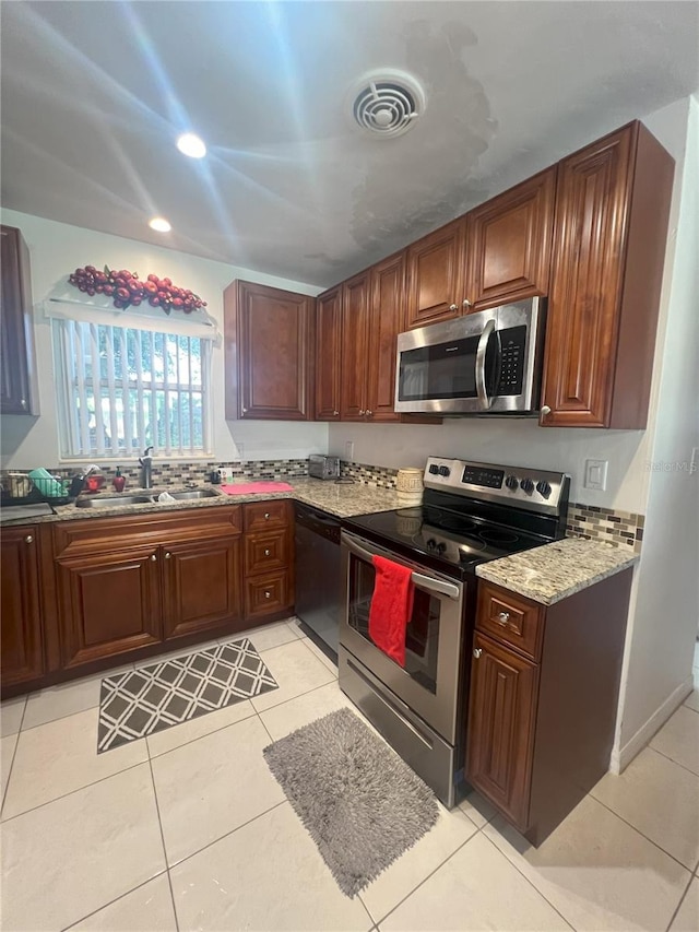 kitchen with sink, light stone countertops, light tile patterned floors, and stainless steel appliances