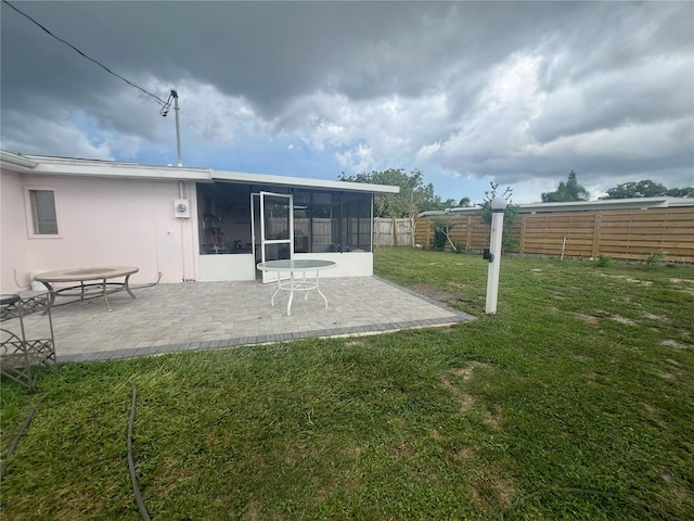 rear view of house featuring a patio, a lawn, and a sunroom