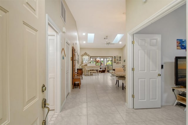 hallway featuring a skylight and light tile patterned flooring