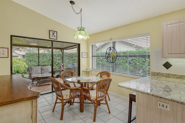 dining space featuring light tile patterned floors, vaulted ceiling, and a wealth of natural light