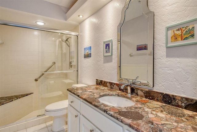 bathroom featuring toilet, tile patterned floors, a shower with door, and vanity