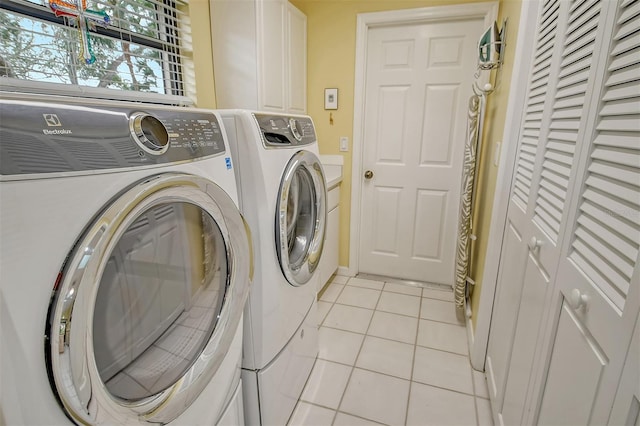 washroom with light tile patterned floors, washing machine and clothes dryer, and cabinets