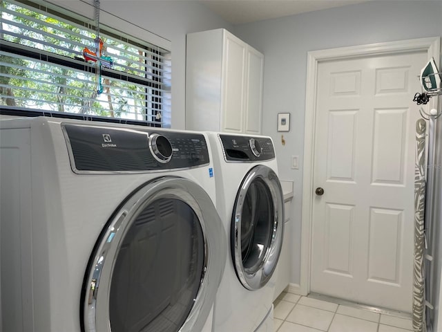 laundry area with washing machine and dryer, cabinet space, and light tile patterned floors