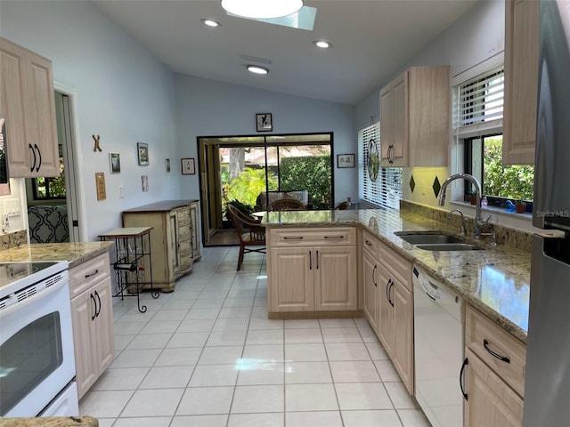 kitchen with a sink, lofted ceiling with skylight, white appliances, light brown cabinets, and light tile patterned floors