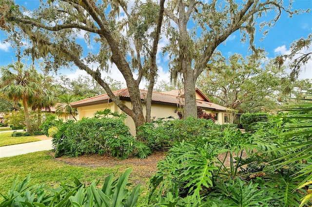 view of home's exterior with an attached garage, driveway, a tiled roof, and stucco siding