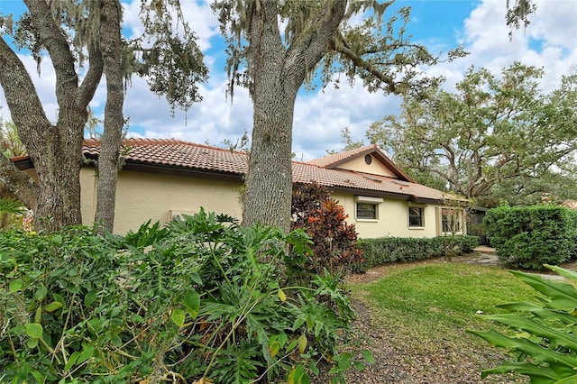 view of side of home with a tile roof and stucco siding