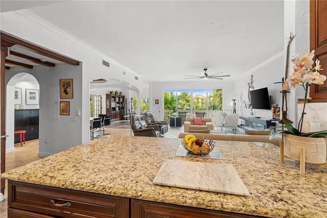 kitchen featuring light tile patterned floors, light stone counters, ceiling fan, and crown molding