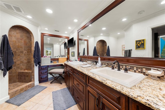 bathroom featuring tile patterned flooring, vanity, ornamental molding, and tiled shower