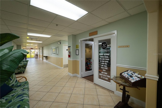 hall featuring a drop ceiling and light tile patterned floors