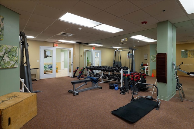 exercise room featuring light colored carpet, a drop ceiling, and french doors