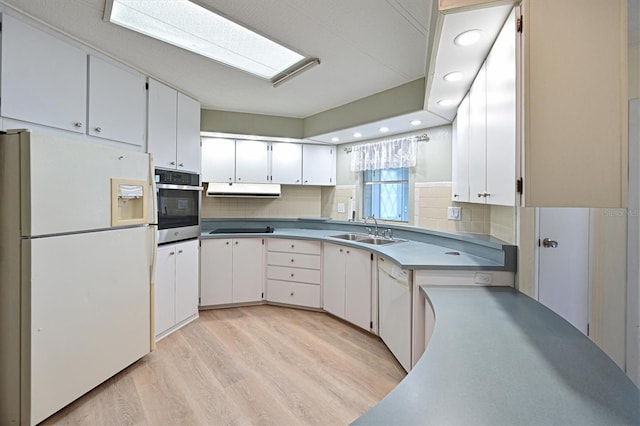 kitchen featuring sink, light wood-type flooring, white cabinetry, white appliances, and a skylight