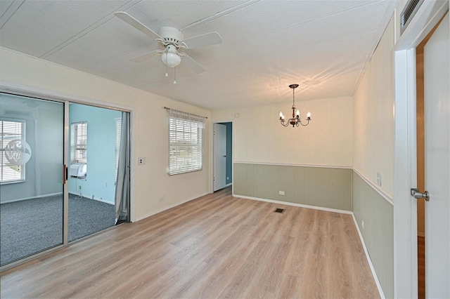 empty room with ceiling fan with notable chandelier, a textured ceiling, light hardwood / wood-style flooring, and cooling unit