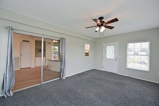 carpeted spare room with ceiling fan and a textured ceiling