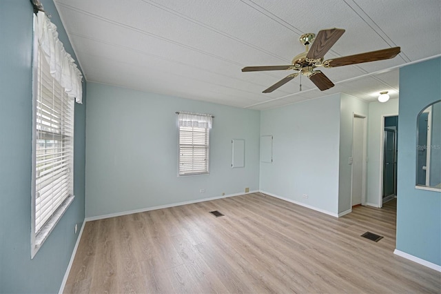 empty room with ceiling fan, a textured ceiling, and light wood-type flooring