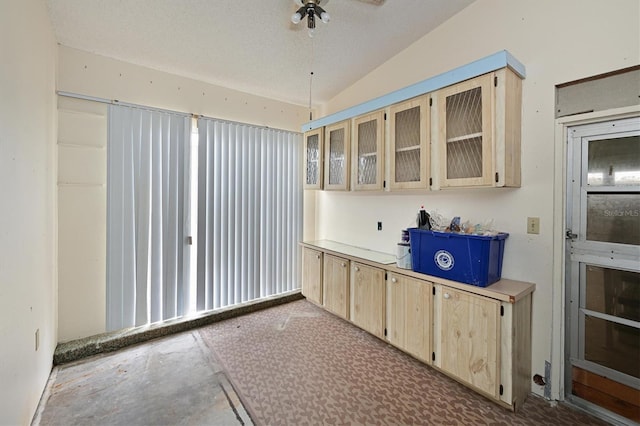 kitchen featuring a textured ceiling, light brown cabinetry, vaulted ceiling, and ceiling fan