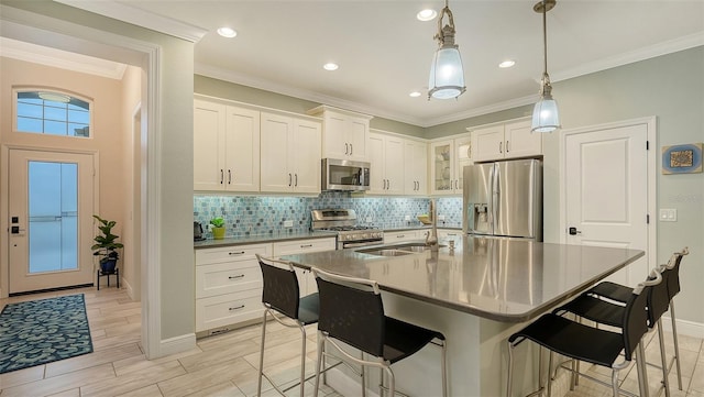 kitchen with stainless steel appliances, white cabinets, a kitchen island with sink, hanging light fixtures, and a breakfast bar