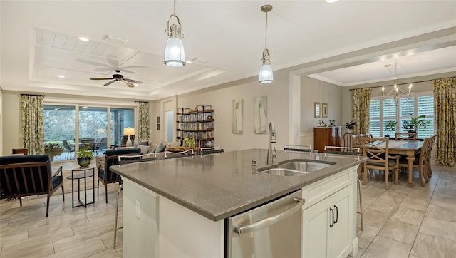 kitchen with ceiling fan with notable chandelier, stainless steel dishwasher, a tray ceiling, and white cabinetry