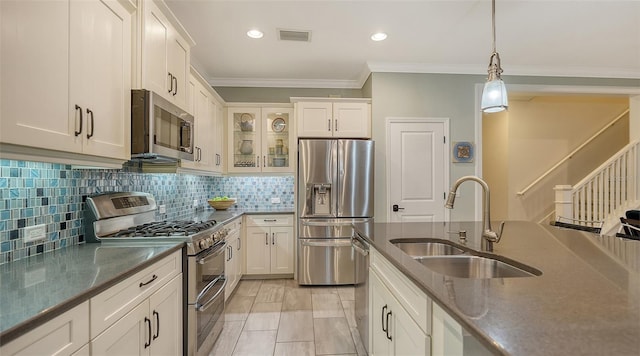 kitchen featuring appliances with stainless steel finishes, sink, white cabinets, decorative light fixtures, and tasteful backsplash