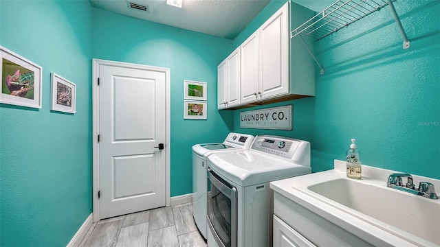 clothes washing area with sink, cabinets, and separate washer and dryer