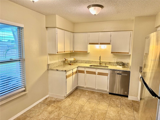 kitchen with white cabinets, light stone counters, sink, and stainless steel appliances