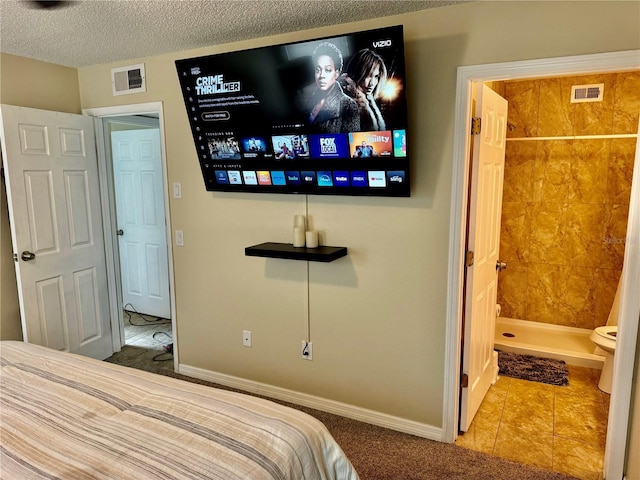 bedroom with tile patterned flooring, a textured ceiling, and connected bathroom