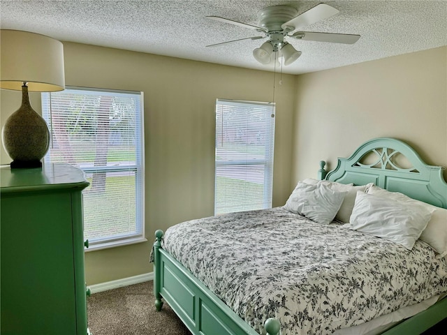 bedroom featuring dark colored carpet, ceiling fan, a textured ceiling, and multiple windows