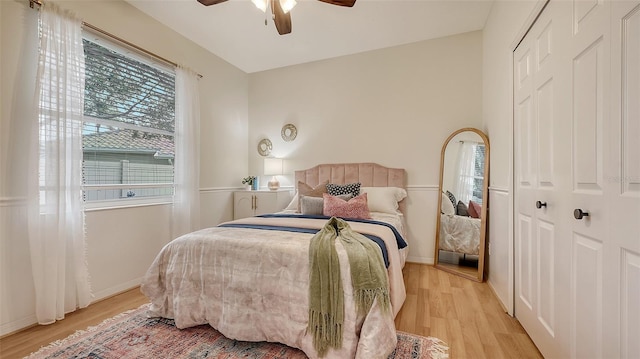 bedroom featuring light wood-style flooring, baseboards, ceiling fan, and a closet