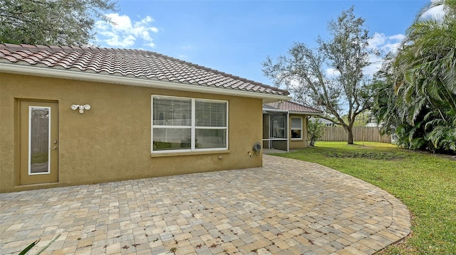 rear view of property with stucco siding, a lawn, a patio area, fence, and a tiled roof