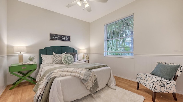 bedroom featuring wainscoting, wood finished floors, and a ceiling fan