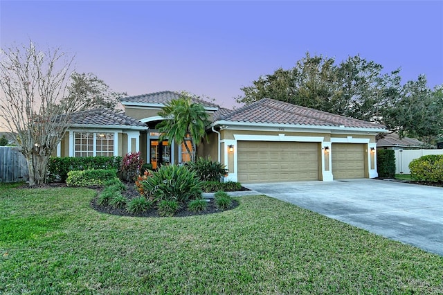 view of front facade with an attached garage, fence, driveway, and a front lawn