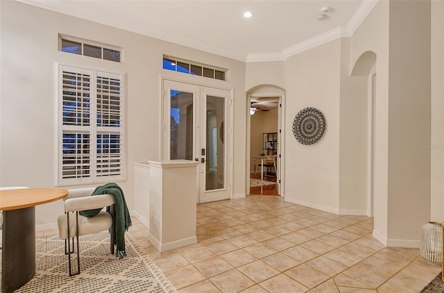 foyer with arched walkways, light tile patterned floors, baseboards, french doors, and ornamental molding