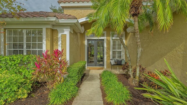 entrance to property with french doors, a tile roof, and stucco siding