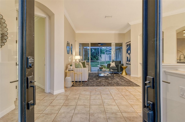 entrance foyer with ceiling fan, crown molding, baseboards, and light tile patterned floors